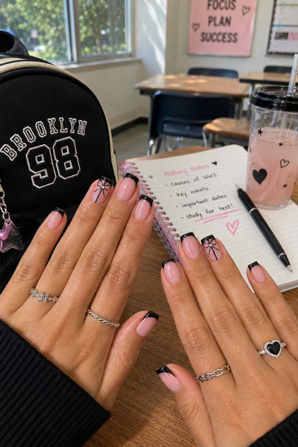 Nude square nails with black French tips and delicate bow line art accents