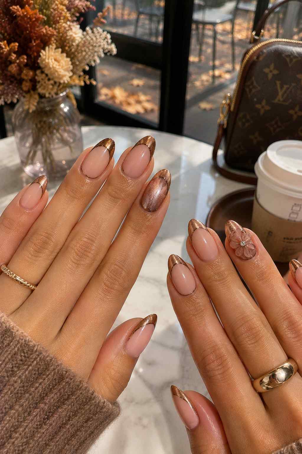 Nude nails with warm bronze cuticle-line French tips and a 3D flower accent nail with a crystal center