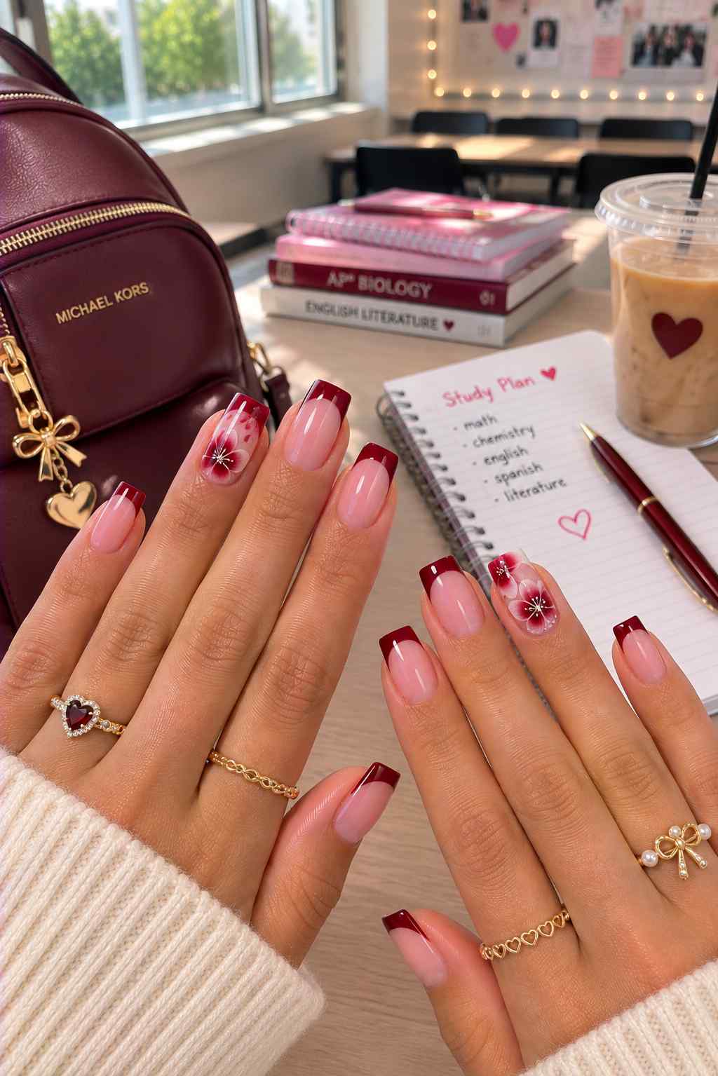 Nude nails with deep burgundy French tips and hand-painted floral accent nails
