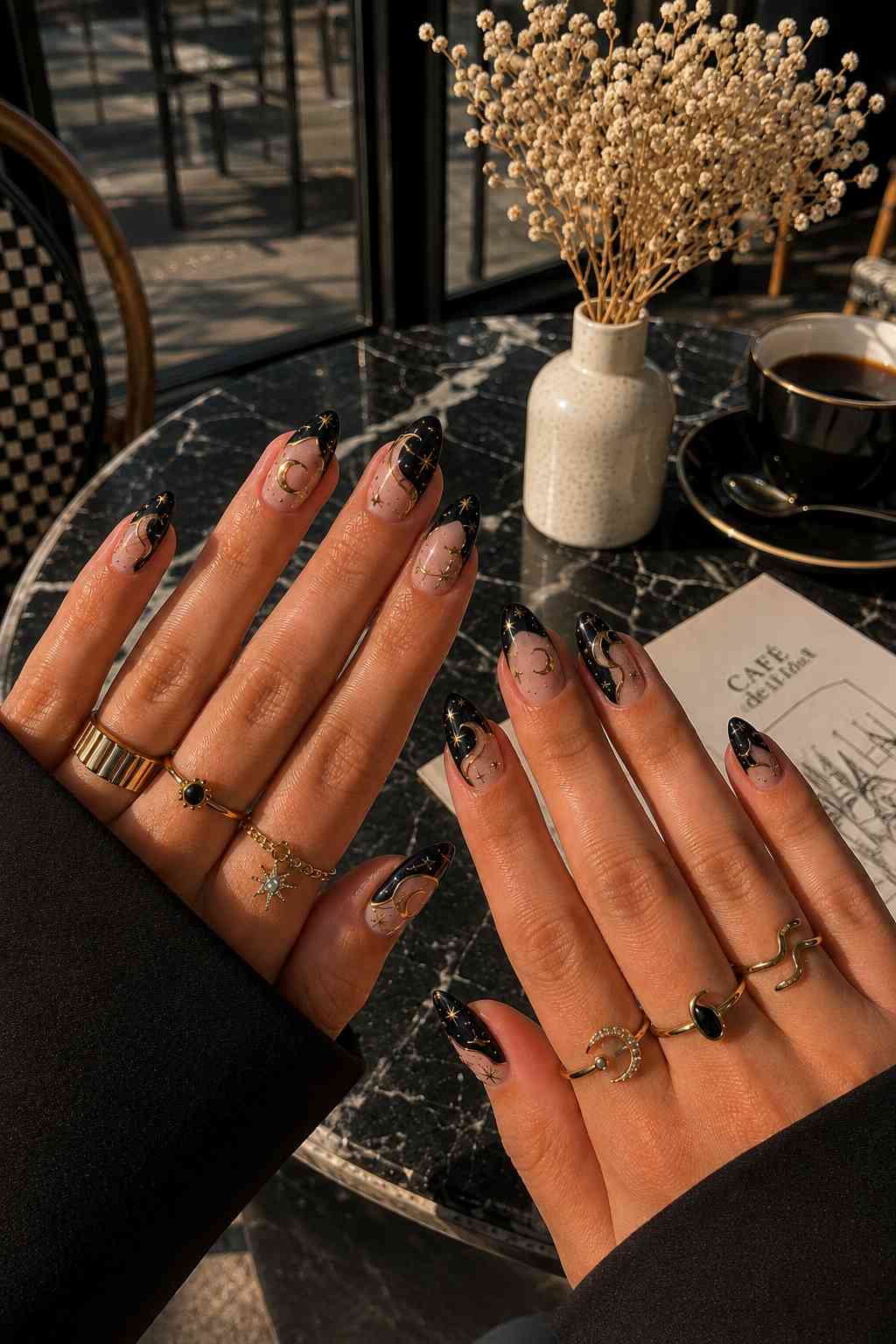 Curved black tip nail art with gold constellation and star detailing on nude base
