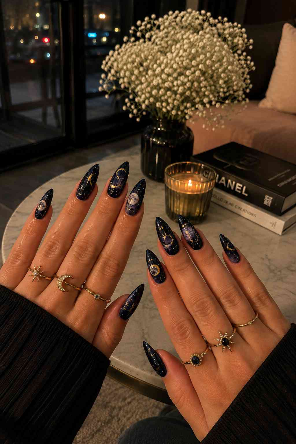 Stiletto almond nails with navy-purple galaxy print, gold constellation art, and moon phase charm