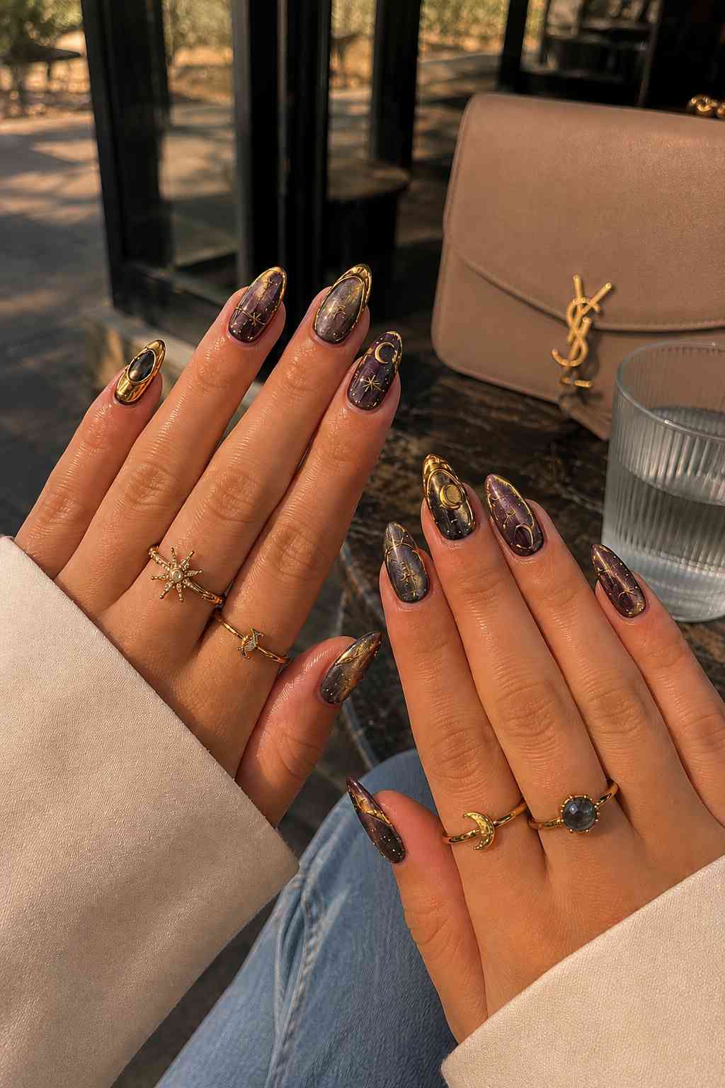 Purple-grey galaxy print nails with gold foil edge and gold moon and sun line art

