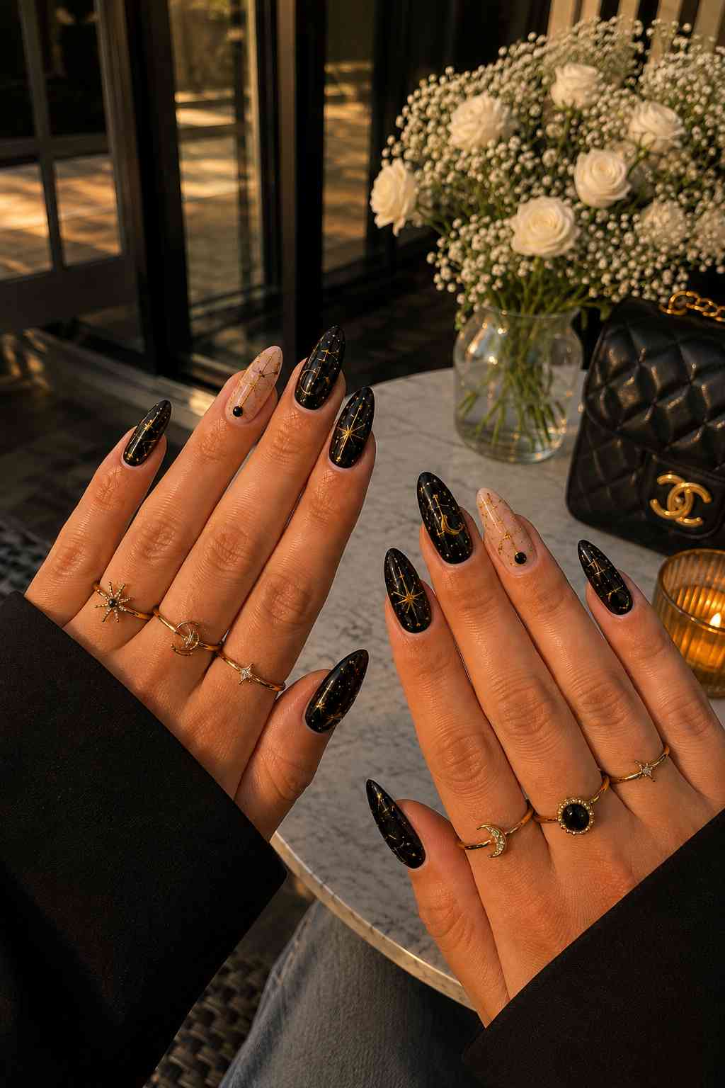 Glossy black almond nails with gold star art and one nude accent nail