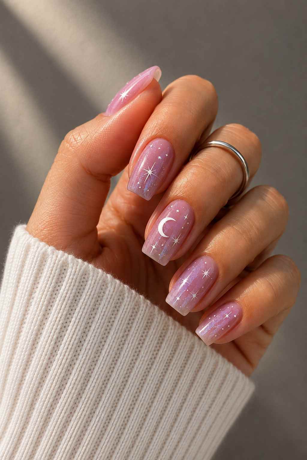 Shimmery lilac-pink nails with silver star and crescent moon accents