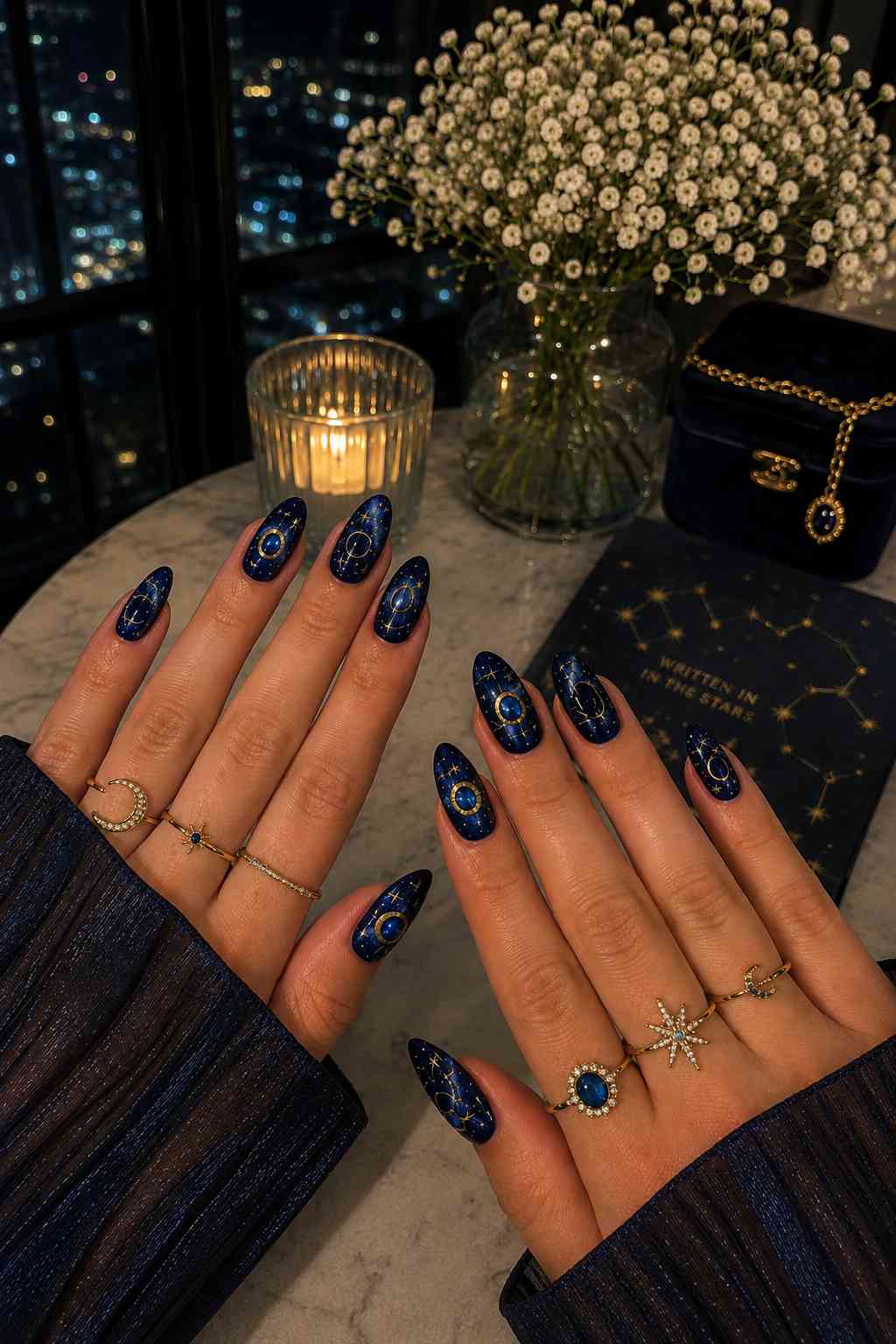Deep navy nails with gold orbit ring outlines and blue gemstone centers