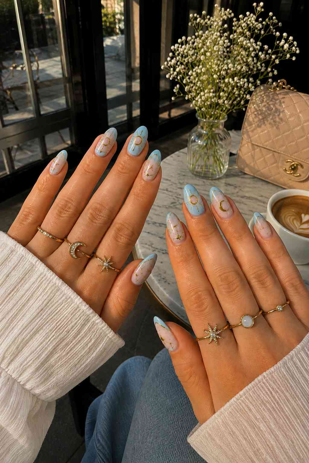 Powder blue and nude nails with gold sun and moon charm nail art