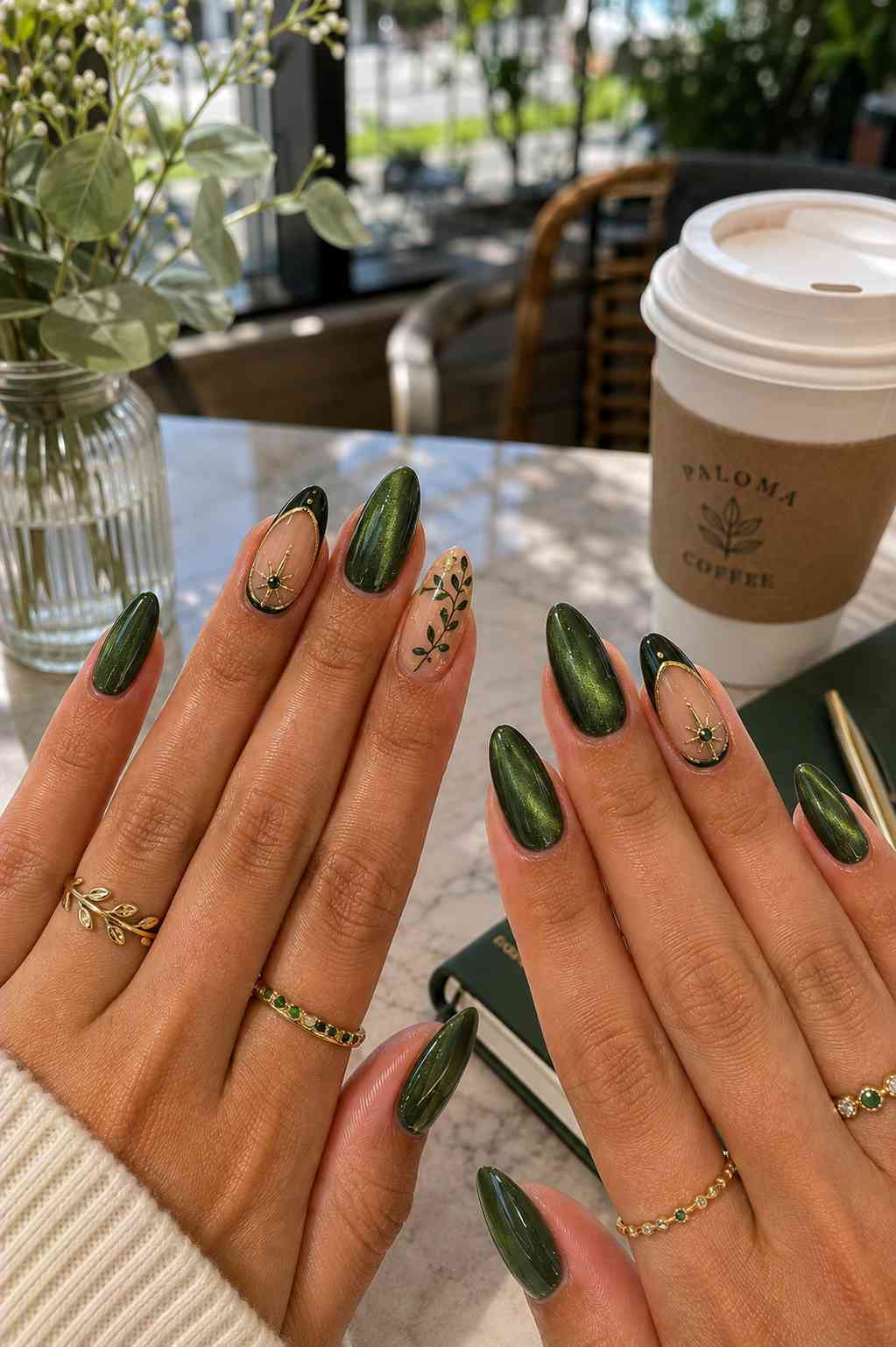 Deep forest green shimmer nails with a gold star charm accent and hand-painted gold leaf branch nail art