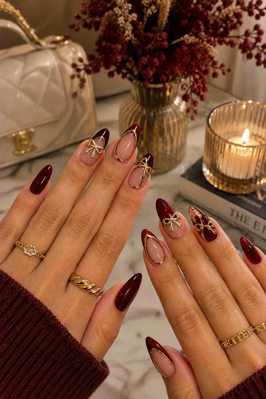 Oxblood nails with sheer nude accents featuring gold bow charms and full gold-outlined French tips