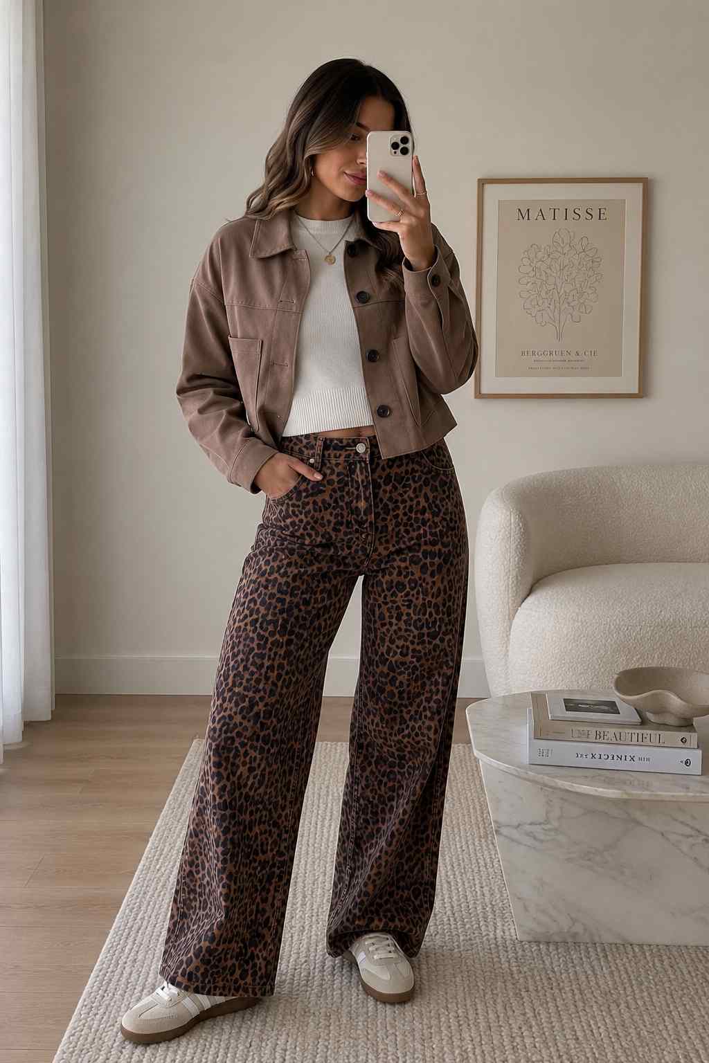 Woman wearing leopard print wide-leg jeans, a cropped brown suede jacket, and a white top for a casual fall outfit.