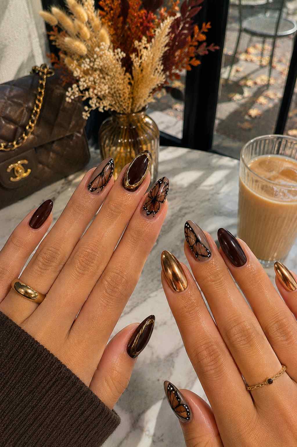Oxblood and bronze chrome nails with sheer nude accent nails featuring hand-painted monarch butterfly wing art