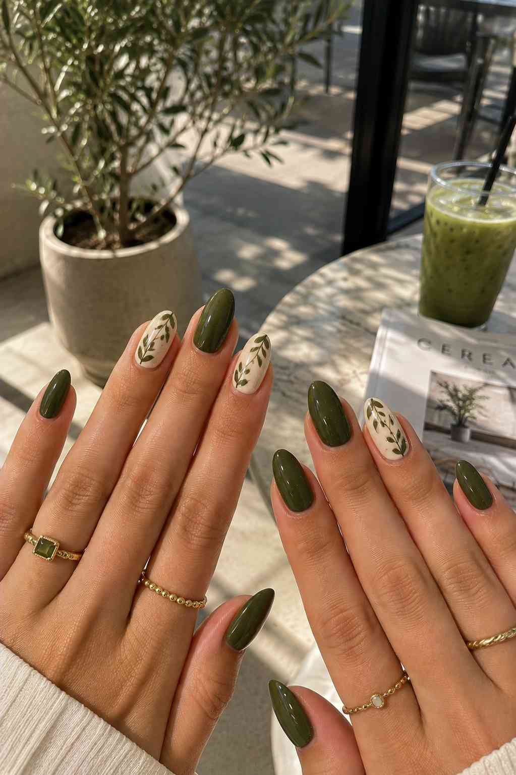 Glossy olive nails alternating with cream nails featuring simple green vine nail art