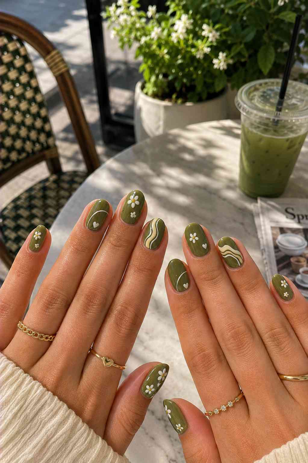 Solid olive nails with white daisy flower art, tiny hearts, and cream swirl line accents