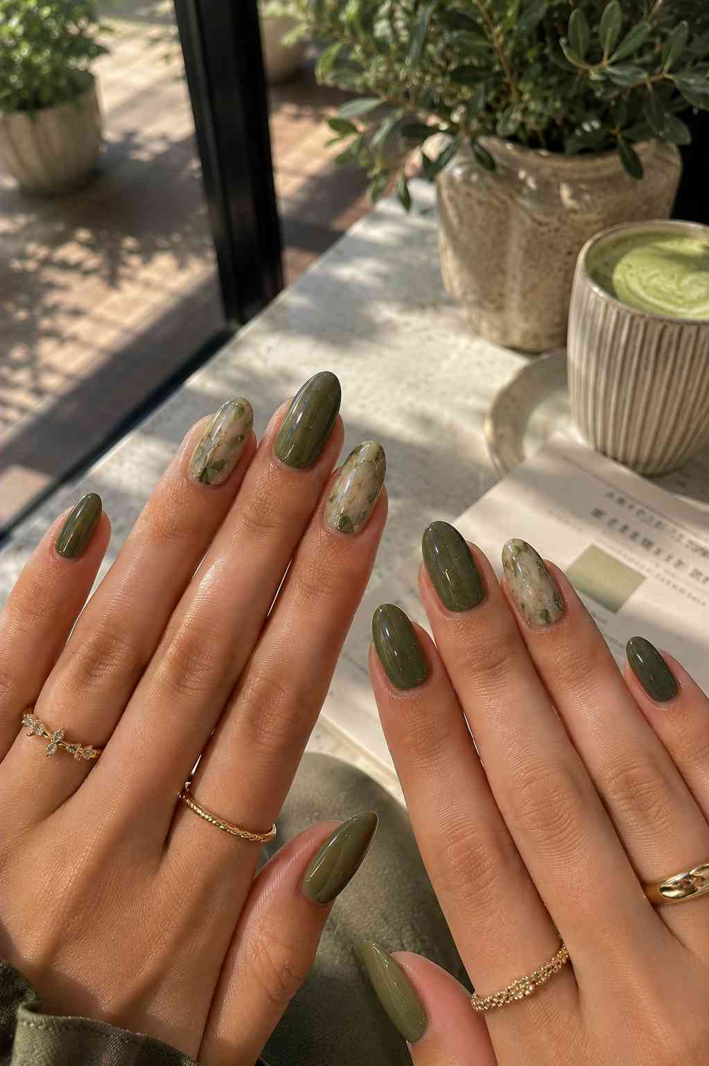 Solid olive nails paired with soft green and nude marbled accent nails