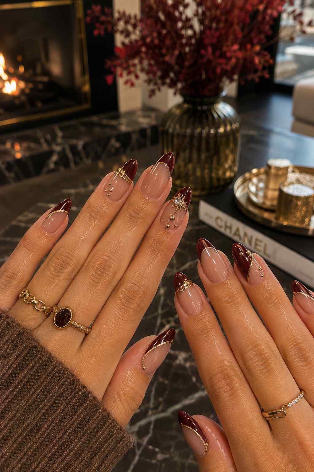 Sheer nude nails with oxblood French tips outlined in gold and a gold star charm accent nail