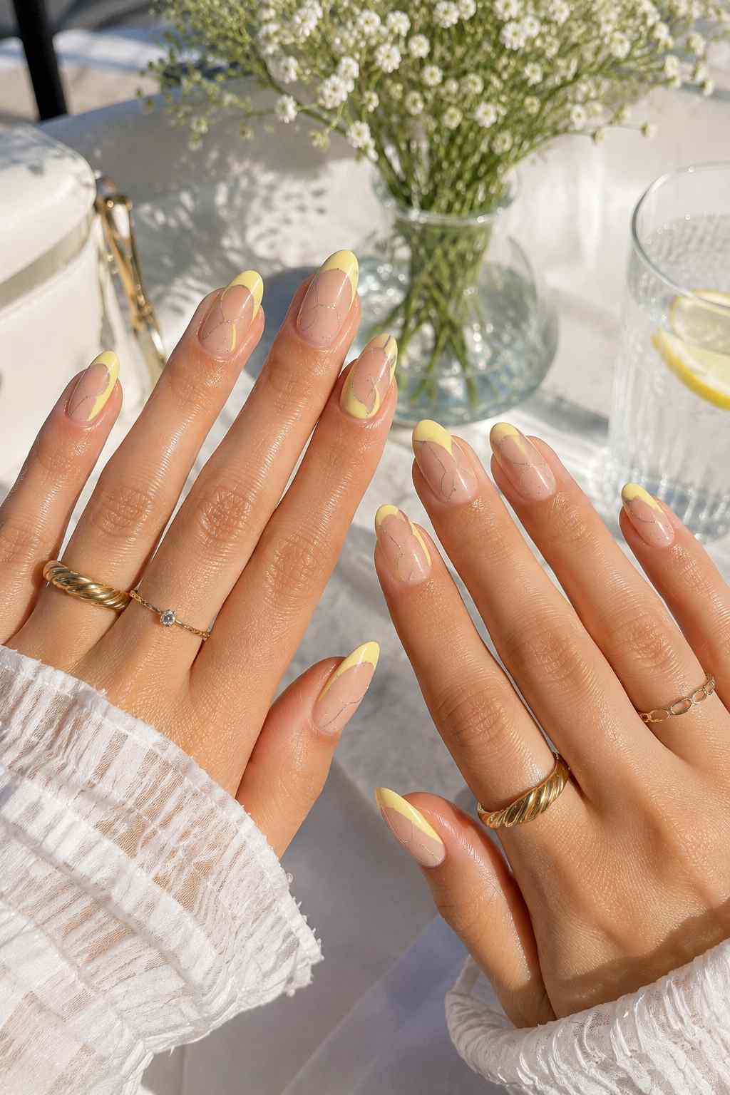 Fine-line marble yellow chrome French tip nails with a sheer nude base
