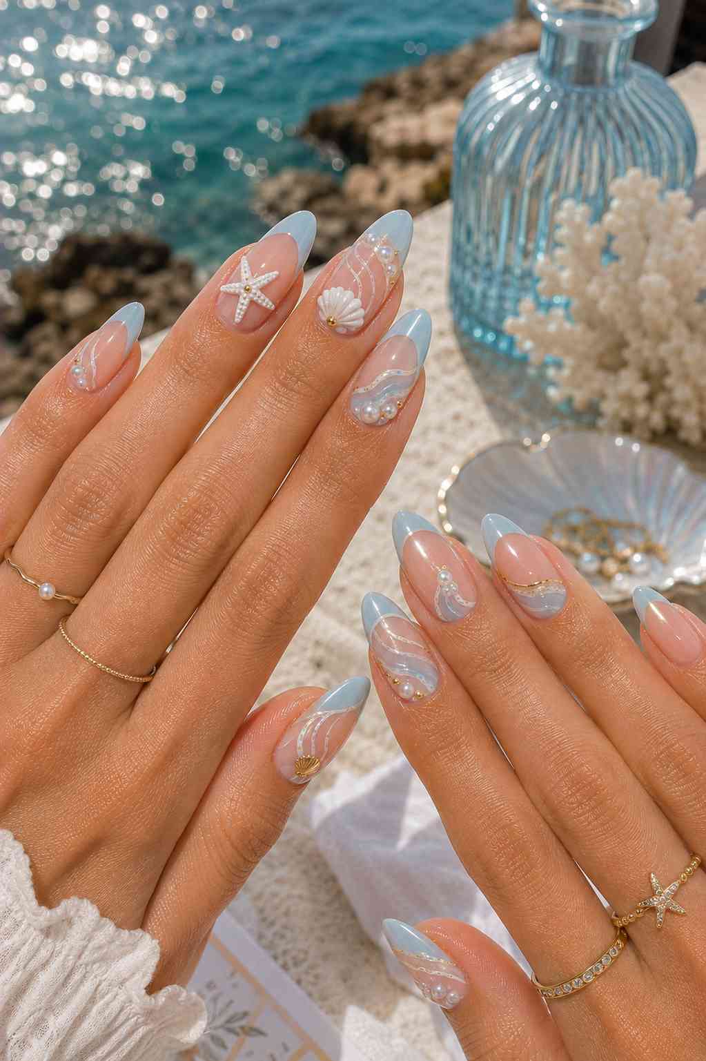 Blue French tip nails with a sculpted shell, starfish, and pearl and gold bead wave line detailing