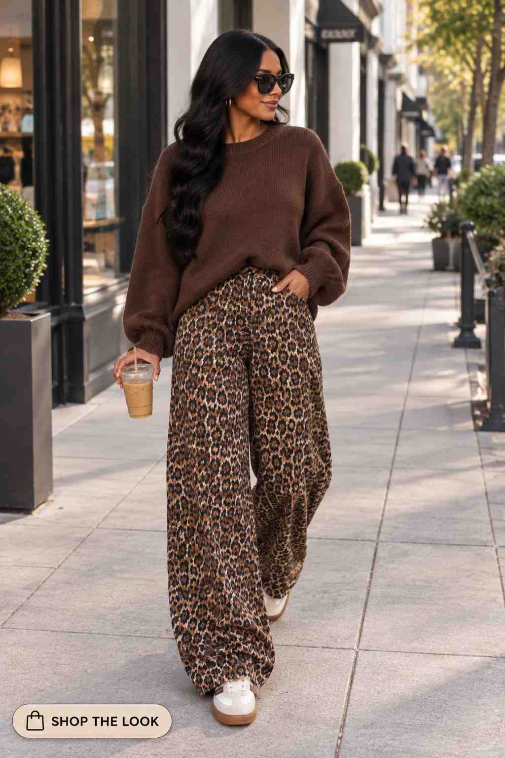 Woman in brown chunky sweater with leopard print wide-leg pants and white sneakers