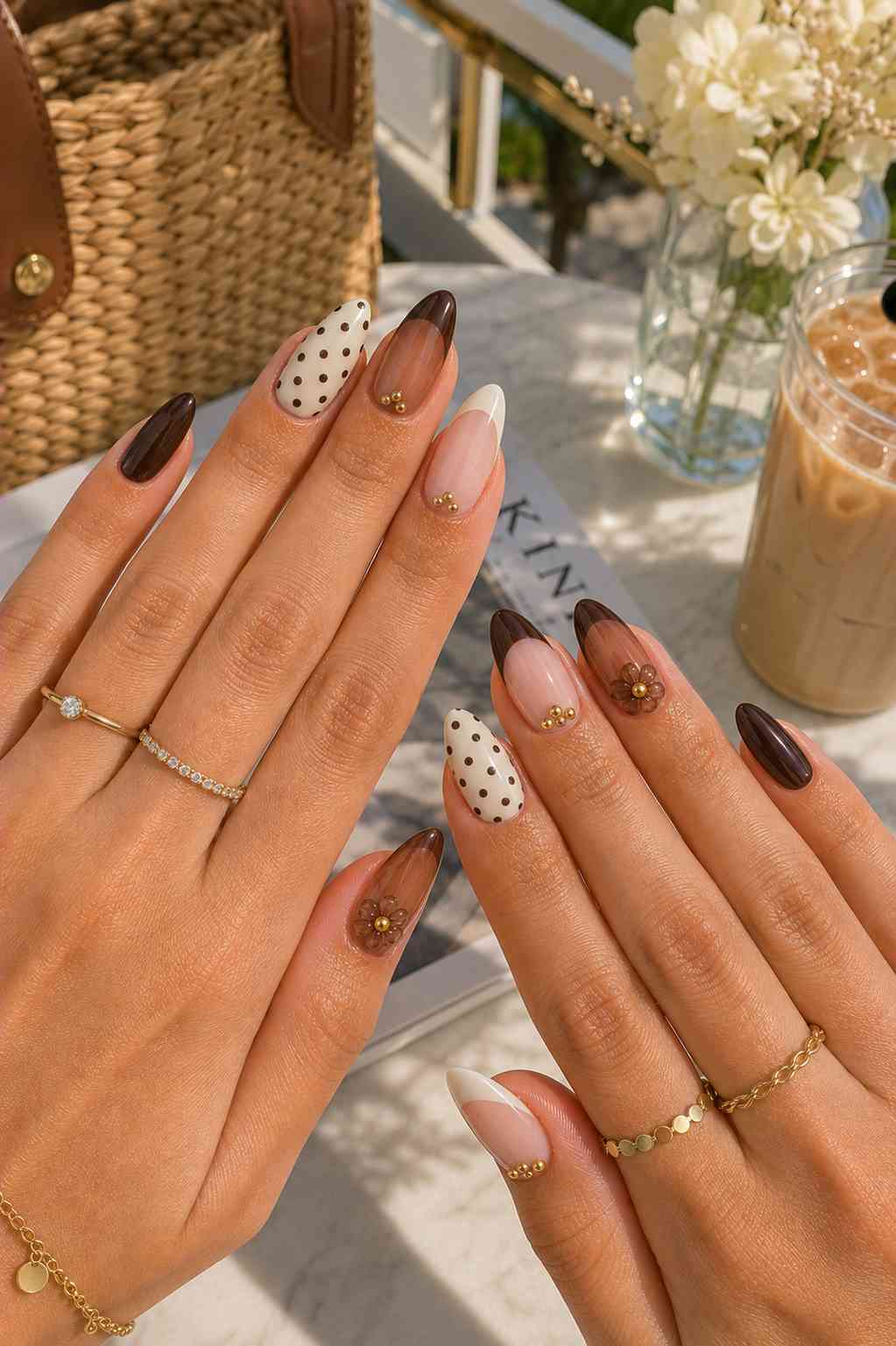 Deep brown and cream nails with polka dots, a French tip, and small 3D flowers with gold centers