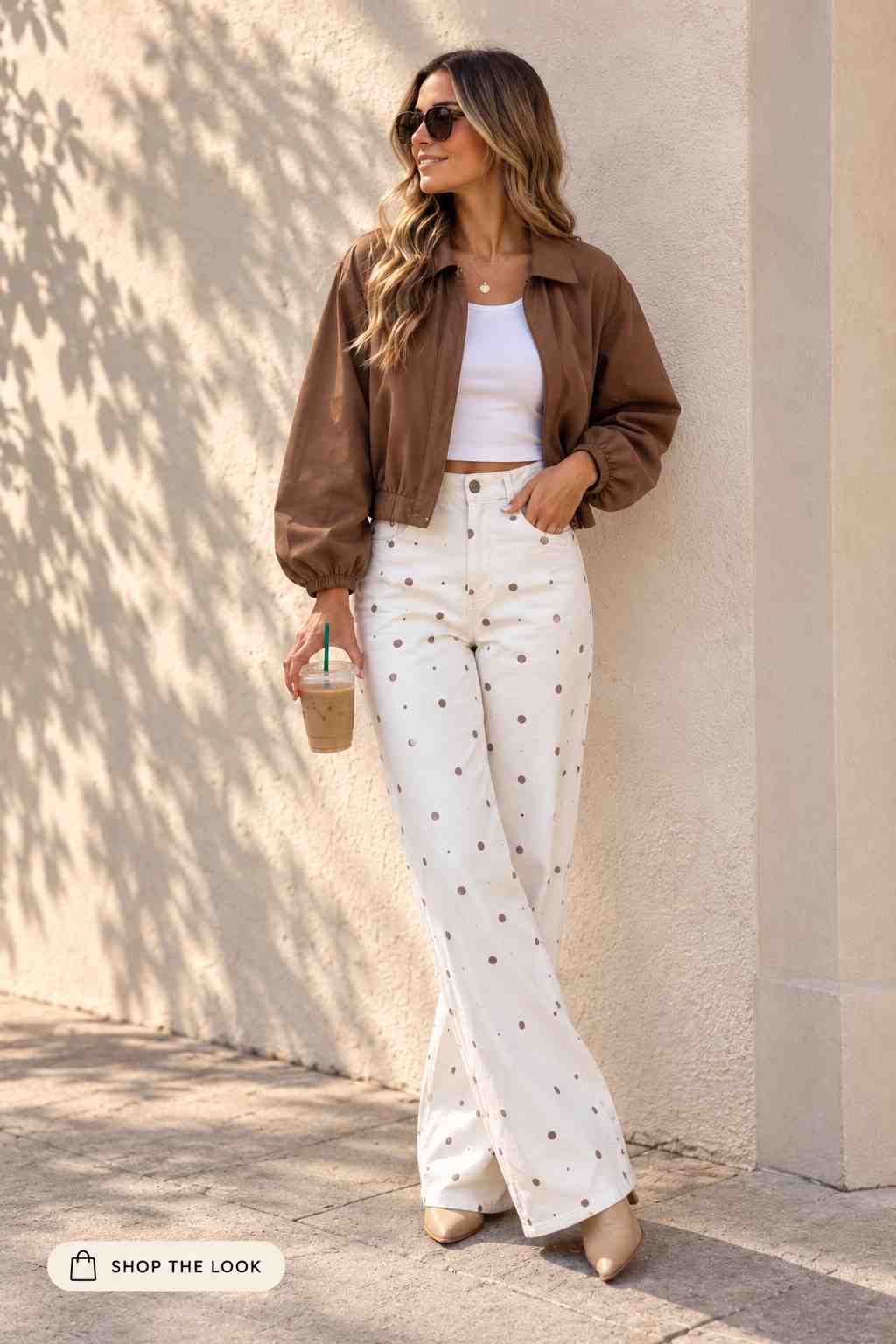 Woman in cropped brown jacket with cream polka dot wide-leg jeans and tan boots