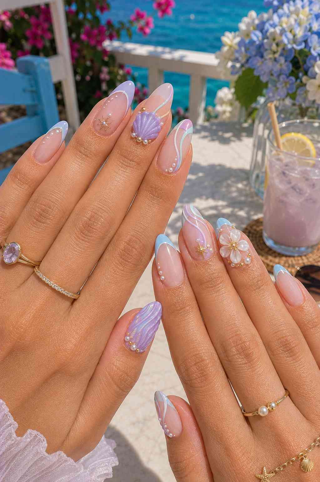 Pale lavender and blue French tip nails with a sculpted shell, star charm, and pearl-framed white flower