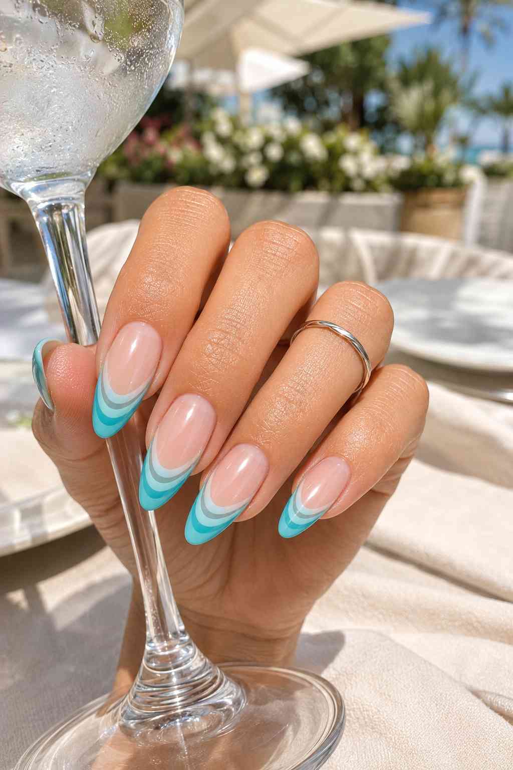 Almond nails with layered turquoise, aqua, gray, and white French tips over a sheer pink base