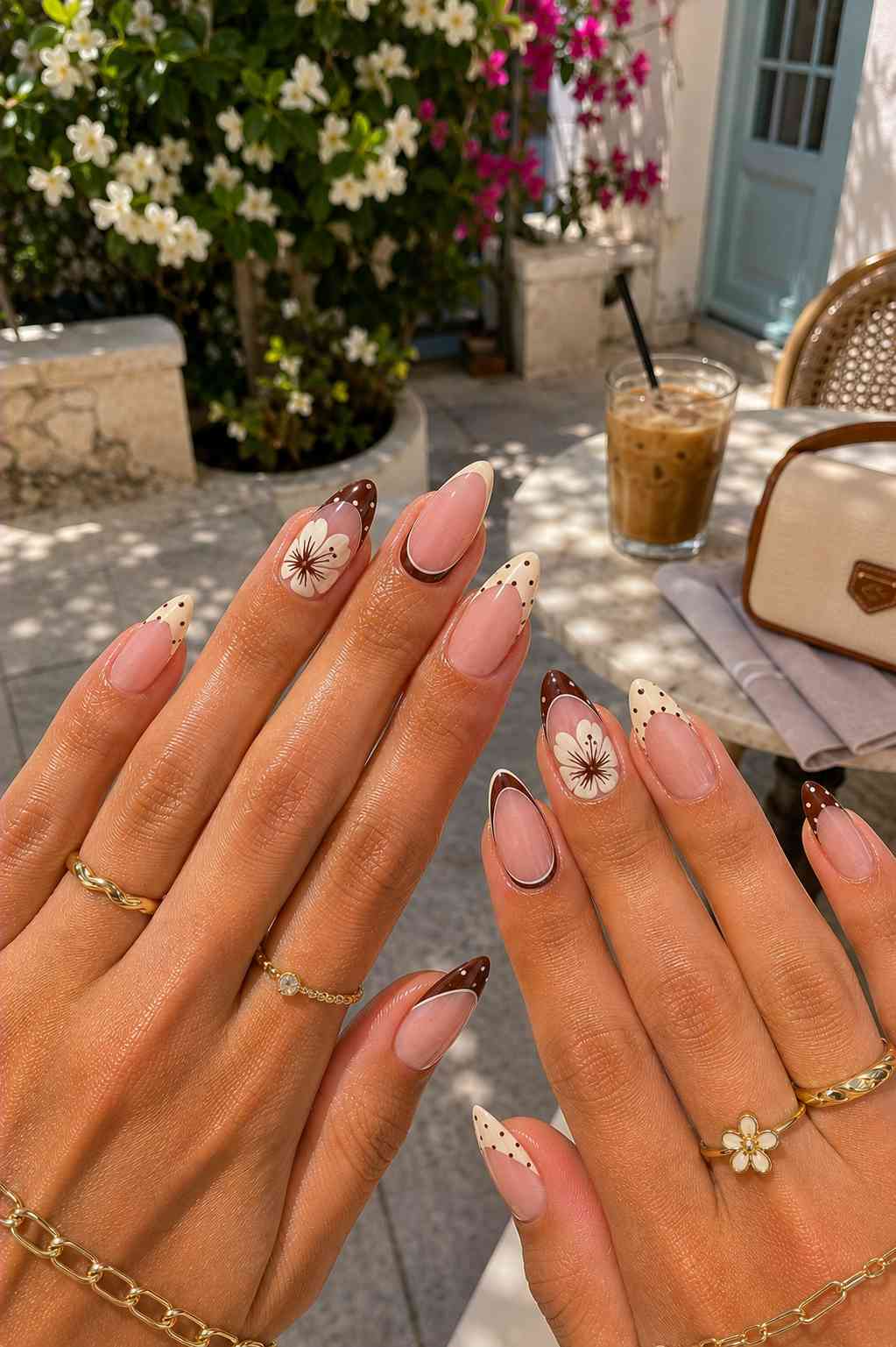 Warm brown French tip nails with polka dots and a hand-painted white flower with a brown center