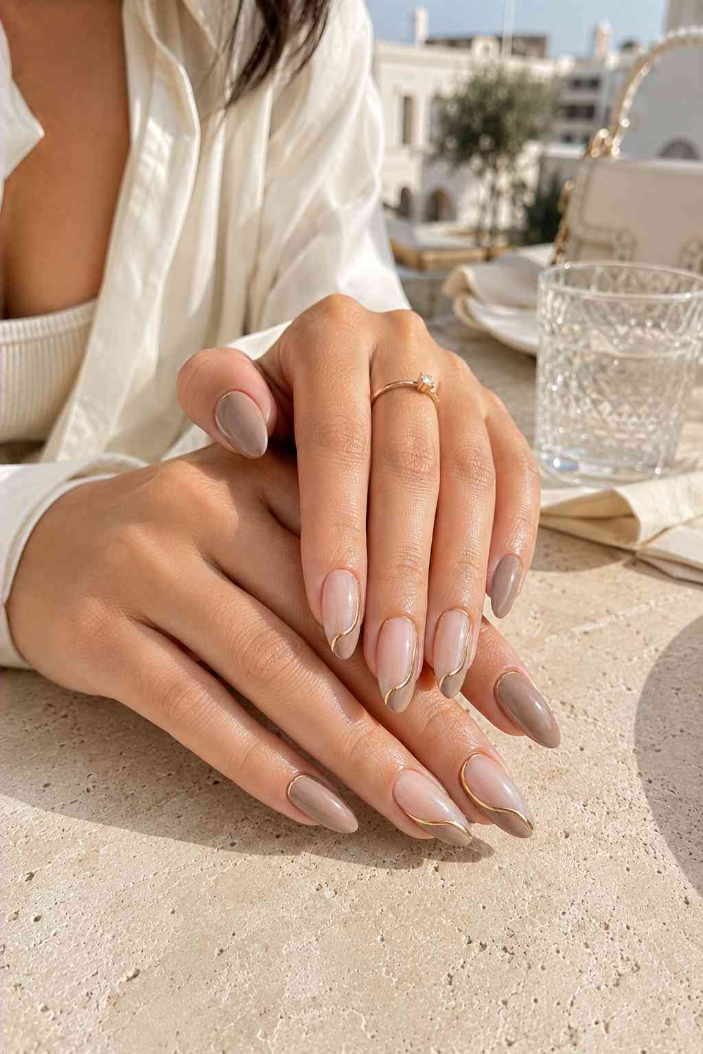 Nude and taupe nails with a thin gold wavy outline accent