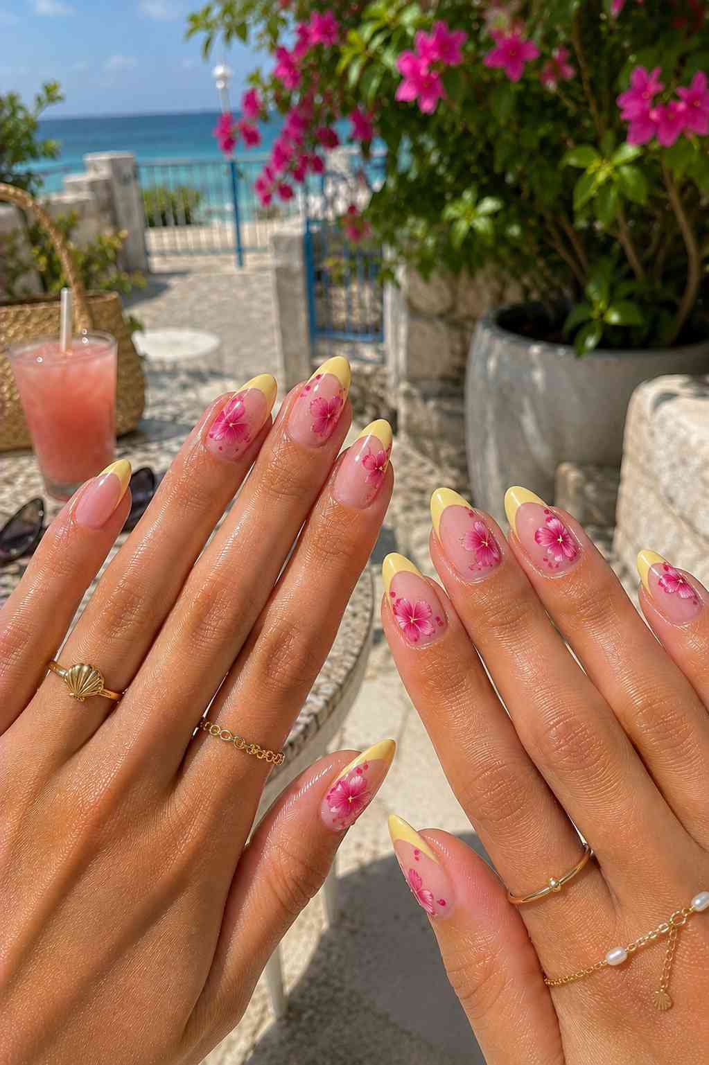 Yellow French tip nails with a single pink flower accent and scattered dot detailing
