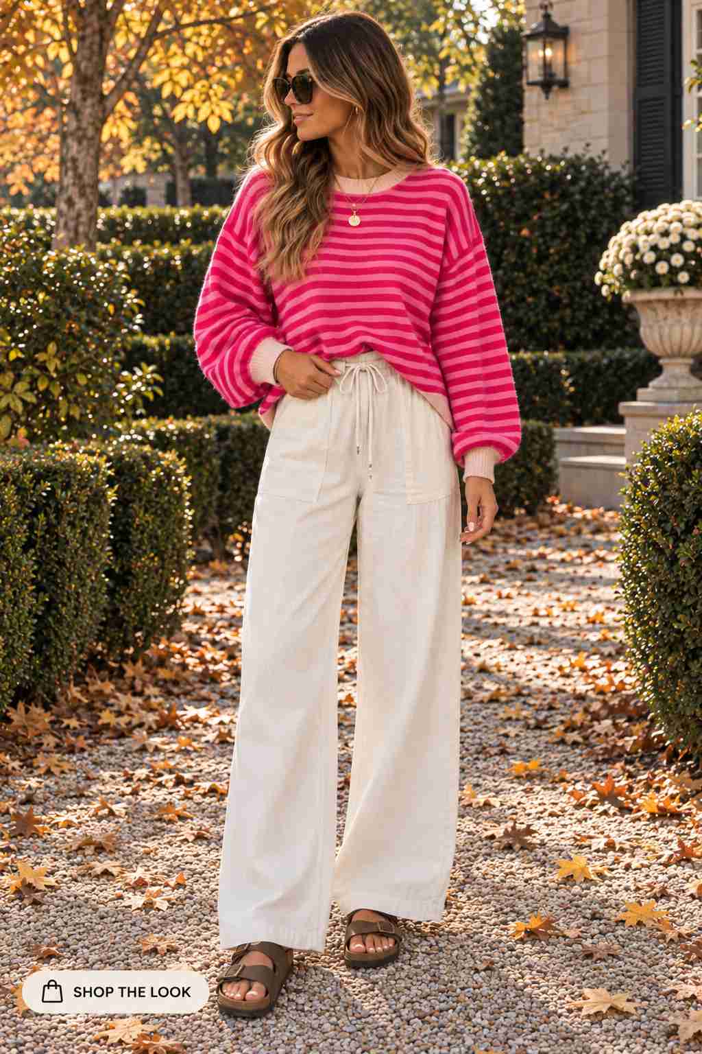 Woman in hot pink striped sweater with cream wide-leg pants and slide sandals