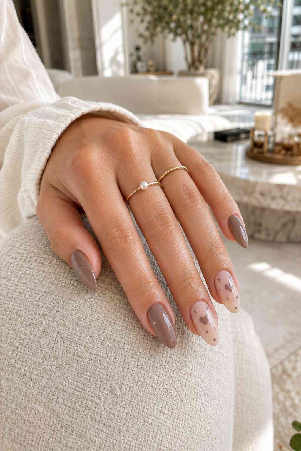Glossy taupe nails with sheer accent nails featuring a brown heart and dot design