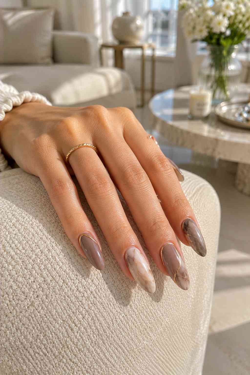 Taupe nails with marbled stone-effect accent nails and gold outline