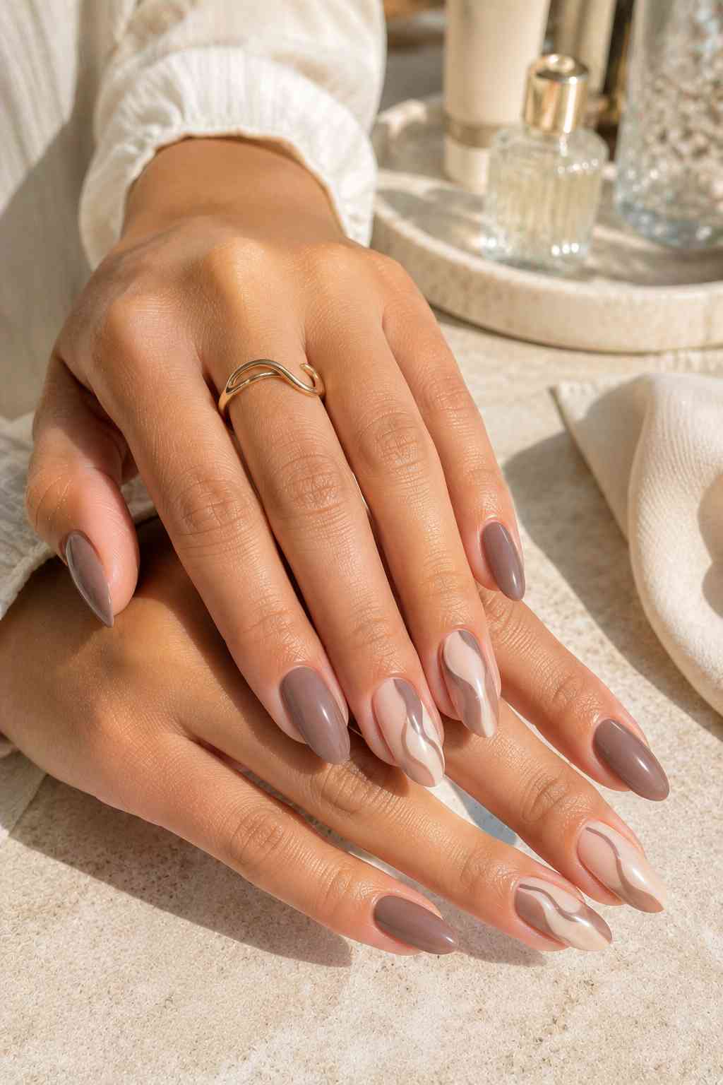 Glossy taupe nails with two nude accent nails featuring brown marbled swirl design
