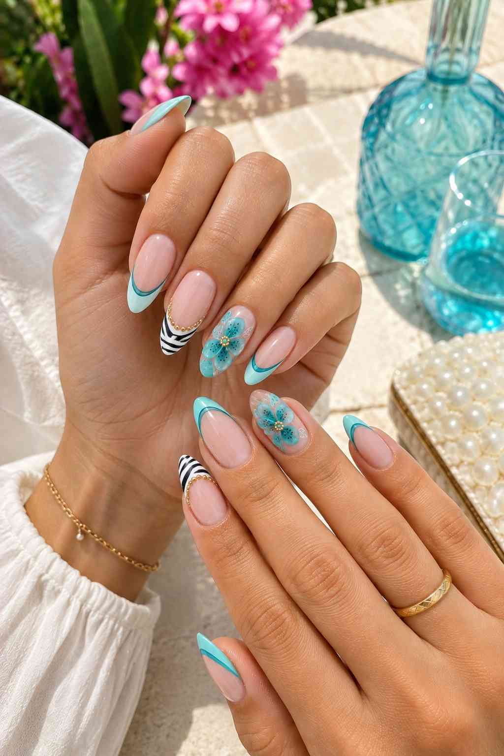 Teal French tip nails with black and white zebra stripes, aqua flowers, and small gold details