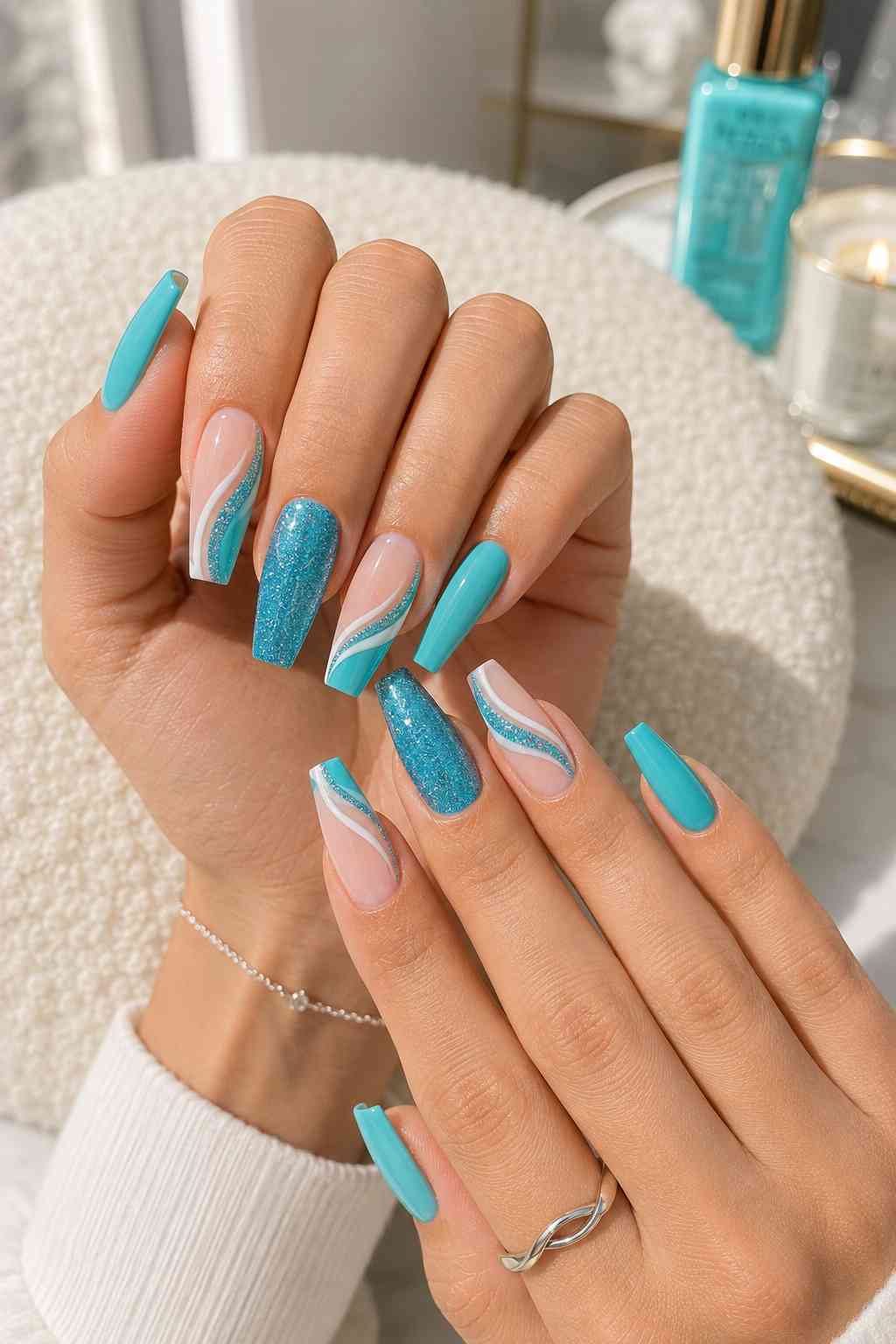 Long turquoise coffin nails with glitter accents and sheer nails featuring white and teal curved lines