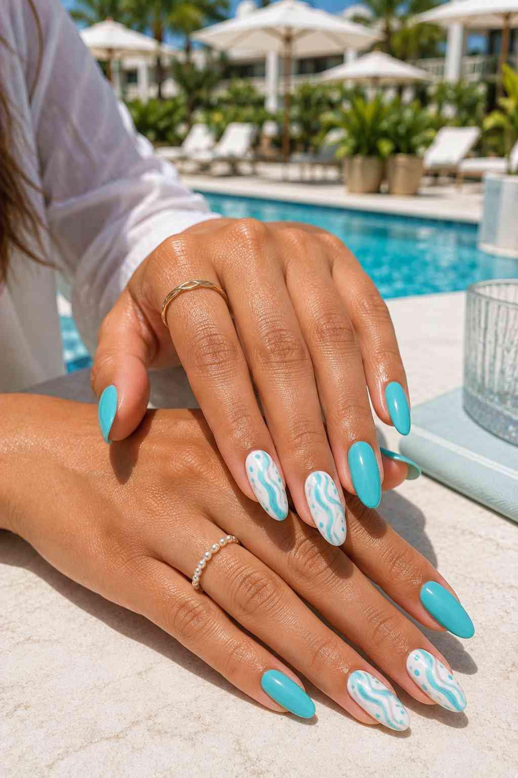 Glossy turquoise almond nails with white accent nails featuring aqua wavy lines and scattered dots