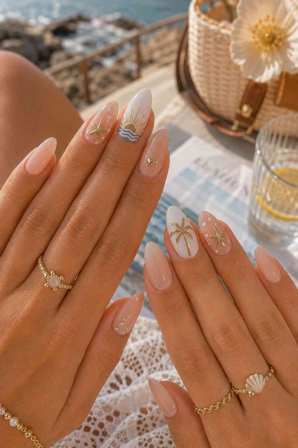 Nude nails with white accent nails featuring a gold palm tree, gold sunburst wave design, and a small gold heart charm